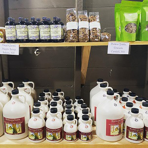 Farm store shelf containing maple syrup, granola, and other local farm-fresh products.